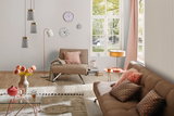 Salon moderne avec meubles rembourrés beiges, coussins roses et lampes décoratives pour une ambiance chaleureuse.