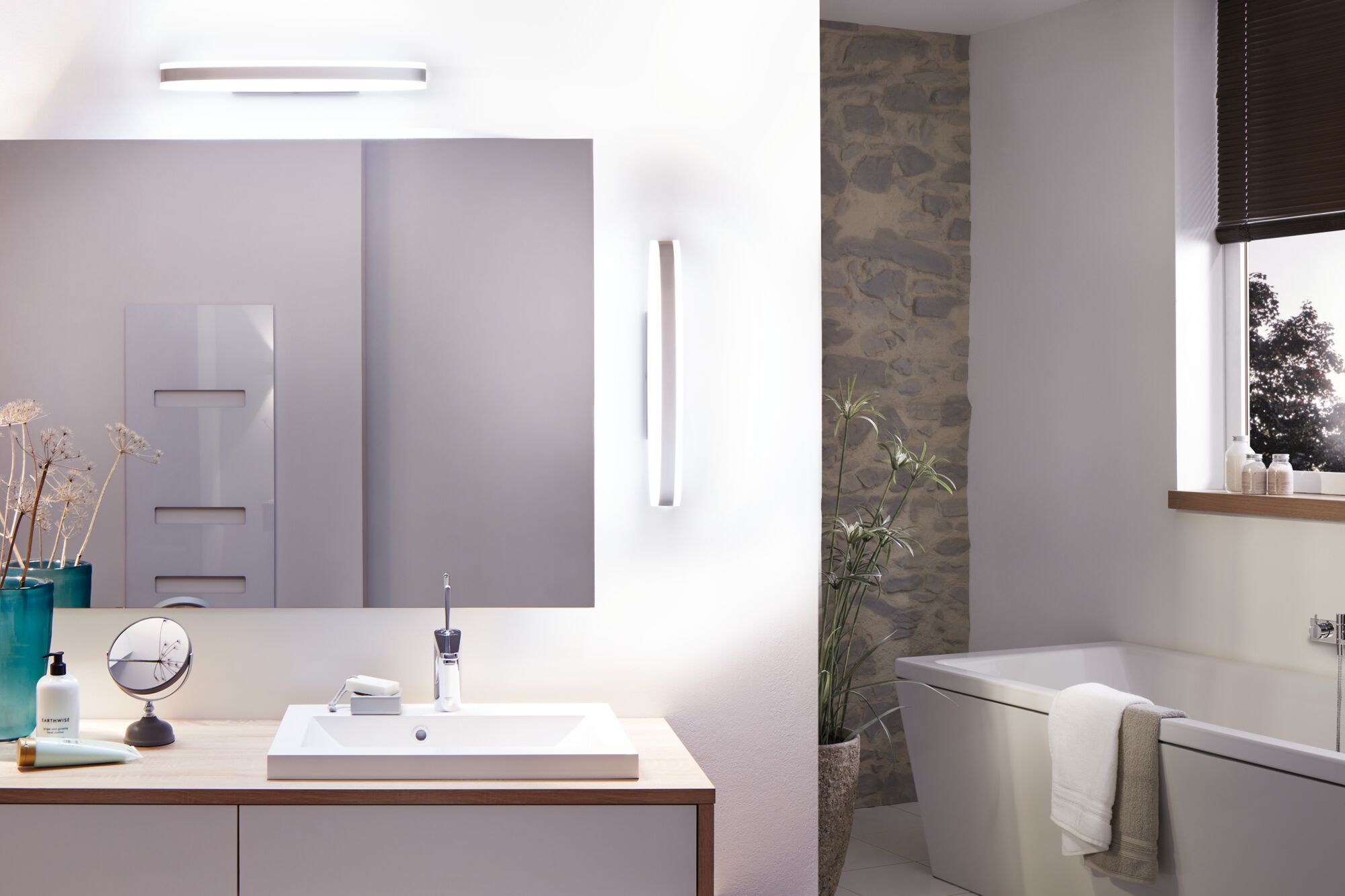 Salle de bain moderne avec lavabo blanc, plan de travail en bois et appliques murales LED minimalistes