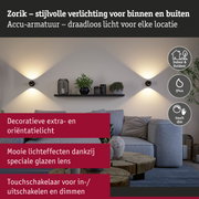 Zwarte wandlampen met warm wit licht aan grijze muur in moderne woonkamer met bank