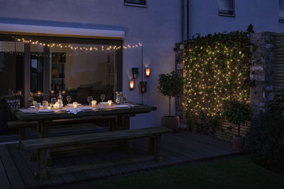 Terrasse accueillante avec banc en bois, table et guirlandes LED blanc chaud pour éclairage extérieur d'ambiance