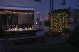 Cozy terrace with wooden bench, table and warm white LED string lights for atmospheric outdoor lighting