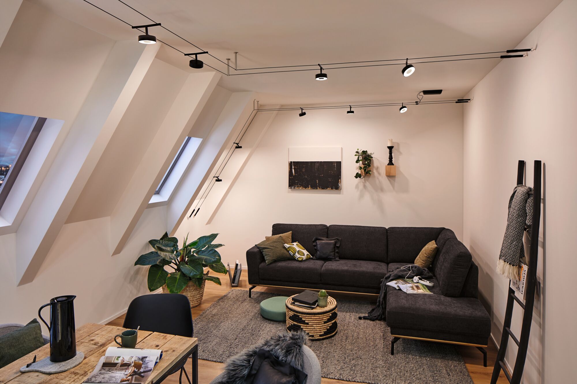 Modernes Wohnzimmer mit schwarzem Ecksofa, grauem Teppich und schwarzer Seilzug-Deckenbeleuchtung für Wohnraum.