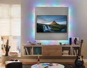 Wohnzimmer mit TV und farbigem LED-Hintergrundlicht, modernes Holz-Medienboard und Gitarre
