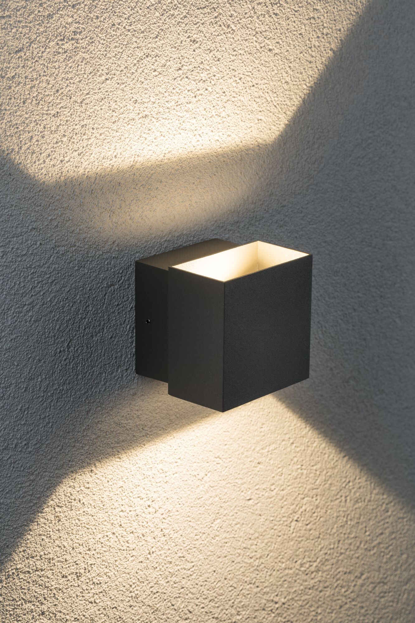 Black aluminum wall light with warm white up and down lighting for modern outdoor illumination.