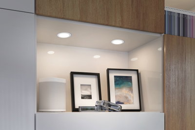 White LED recessed lights in modern kitchen niche with speaker and framed pictures.