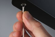 Nahaufnahme einer Hand, die ein silbernes, geflochtenes Kabel an einem schwarzen Metallteil hält, LED-Zubehör