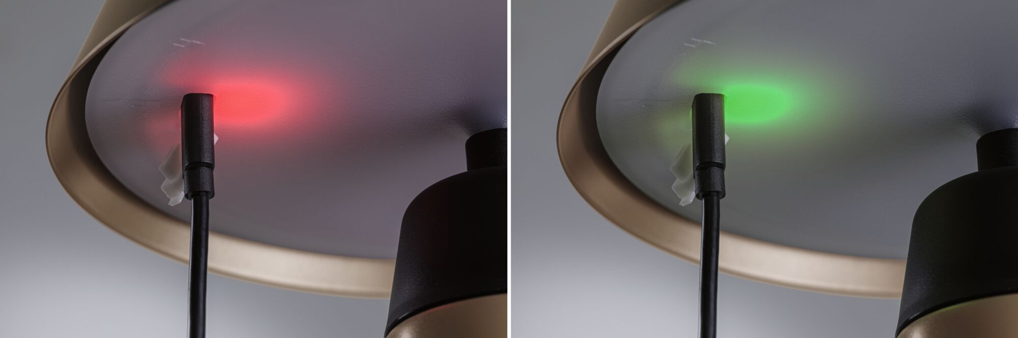 Nahaufnahme einer Lampe mit schwarzem Kabel und rotem sowie grünem LED-Anzeigelicht am Lampenschirmrand