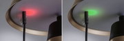 Nahaufnahme einer Lampe mit schwarzem Kabel und rotem sowie grünem LED-Anzeigelicht am Lampenschirmrand