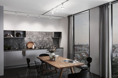 Modern dining room with wooden table, black chairs, grey stone-effect kitchen backsplash, and LED ceiling spotlights