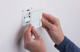 White plastic LED wall recessed light being installed by hands, modern indoor lighting fixture