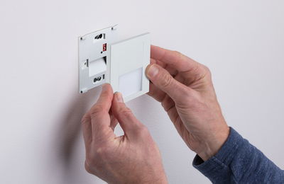 White plastic LED wall recessed light being installed by hands, modern indoor lighting fixture