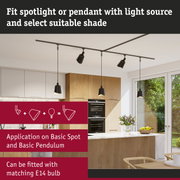 Black pendant lights and spotlights on track system in modern kitchen with wood cabinets and marble countertop