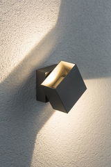 Moderne zwarte aluminium wandspot met warm wit licht op gestructureerde muur voor buitenverlichting
