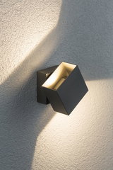 Moderner schwarzer Aluminium-Wandstrahler mit warmweißem Licht an strukturierter Wand für Außenbeleuchtung