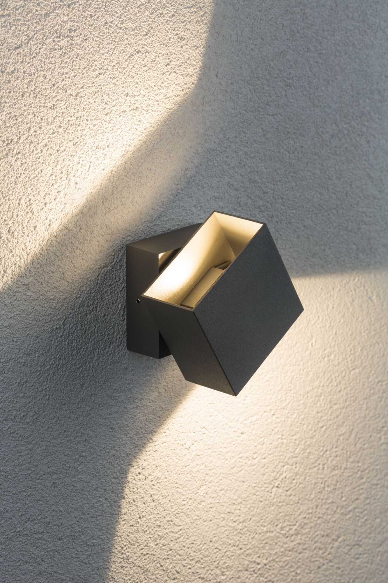 Moderner schwarzer Aluminium-Wandstrahler mit warmweißem Licht an strukturierter Wand für Außenbeleuchtung