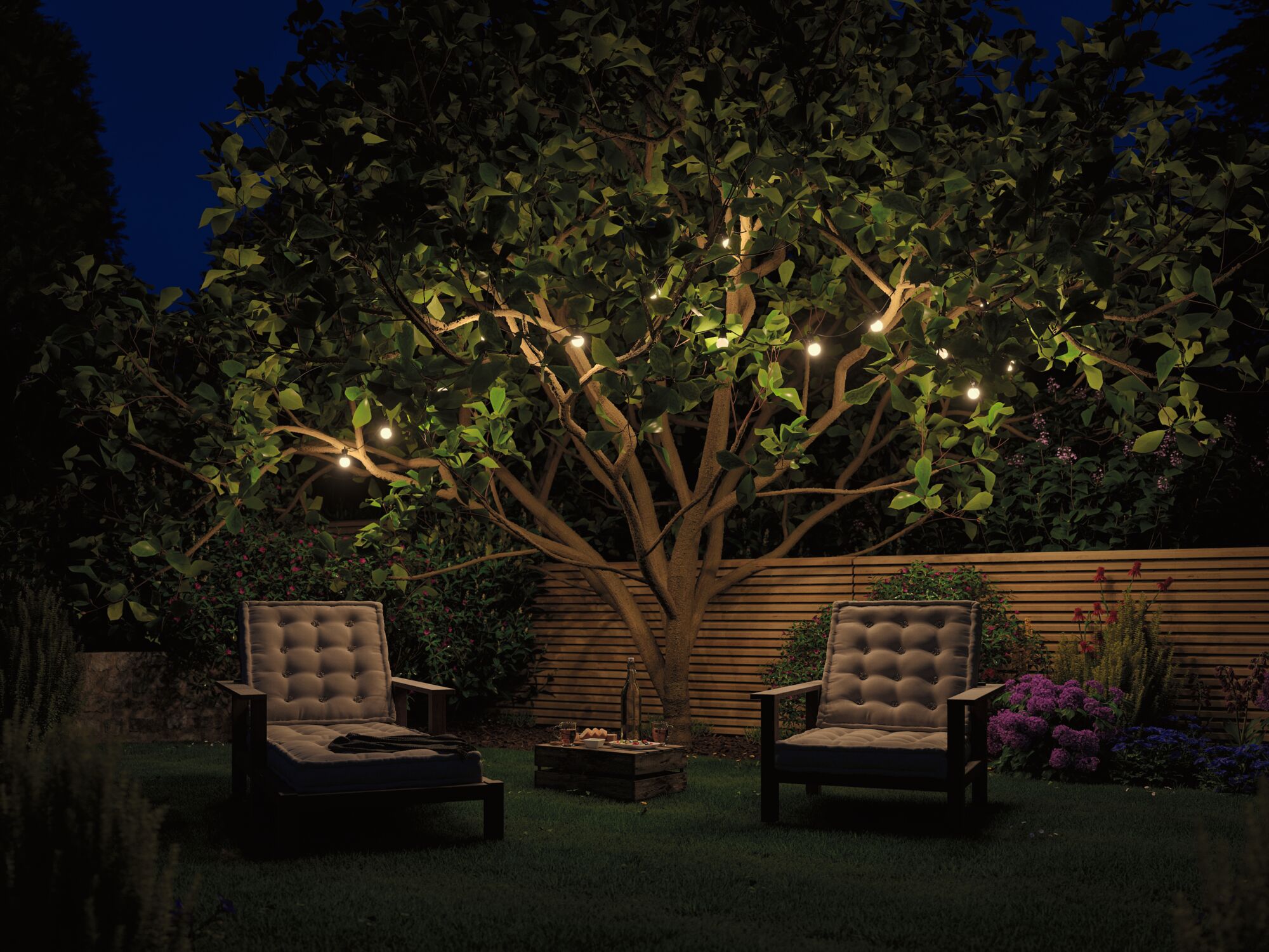 Gemütliche Gartenstühle mit Polster vor beleuchtetem Baum und Holzzaun bei Nacht für Außenbeleuchtung