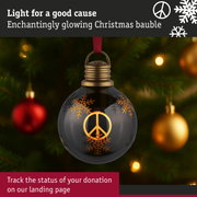 Black Christmas bauble with golden peace sign and snowflakes, glowing on a decorated tree