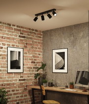 Spots de plafond noirs en métal avec quatre lampes réglables dans un bureau moderne avec mur en briques