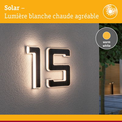 Numéro de maison solaire 15 en matériau noir avec lumière LED blanc chaud sur mur gris