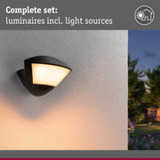 Black outdoor wall light with warm white glow on white wall, modern garden lighting fixture