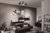 Plafonnier noir à trois spots réglables dans un salon moderne avec canapé marron.