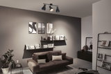 Plafonnier noir à trois spots réglables dans un salon moderne avec canapé marron.