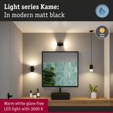 Matt black Kame LED light series with warm white 3000K glow in modern bathroom setting with mirror.