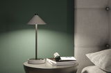 Lampe de table moderne grise en métal avec abat-jour en tissu sur table de chevet près d'un lit rembourré gris.