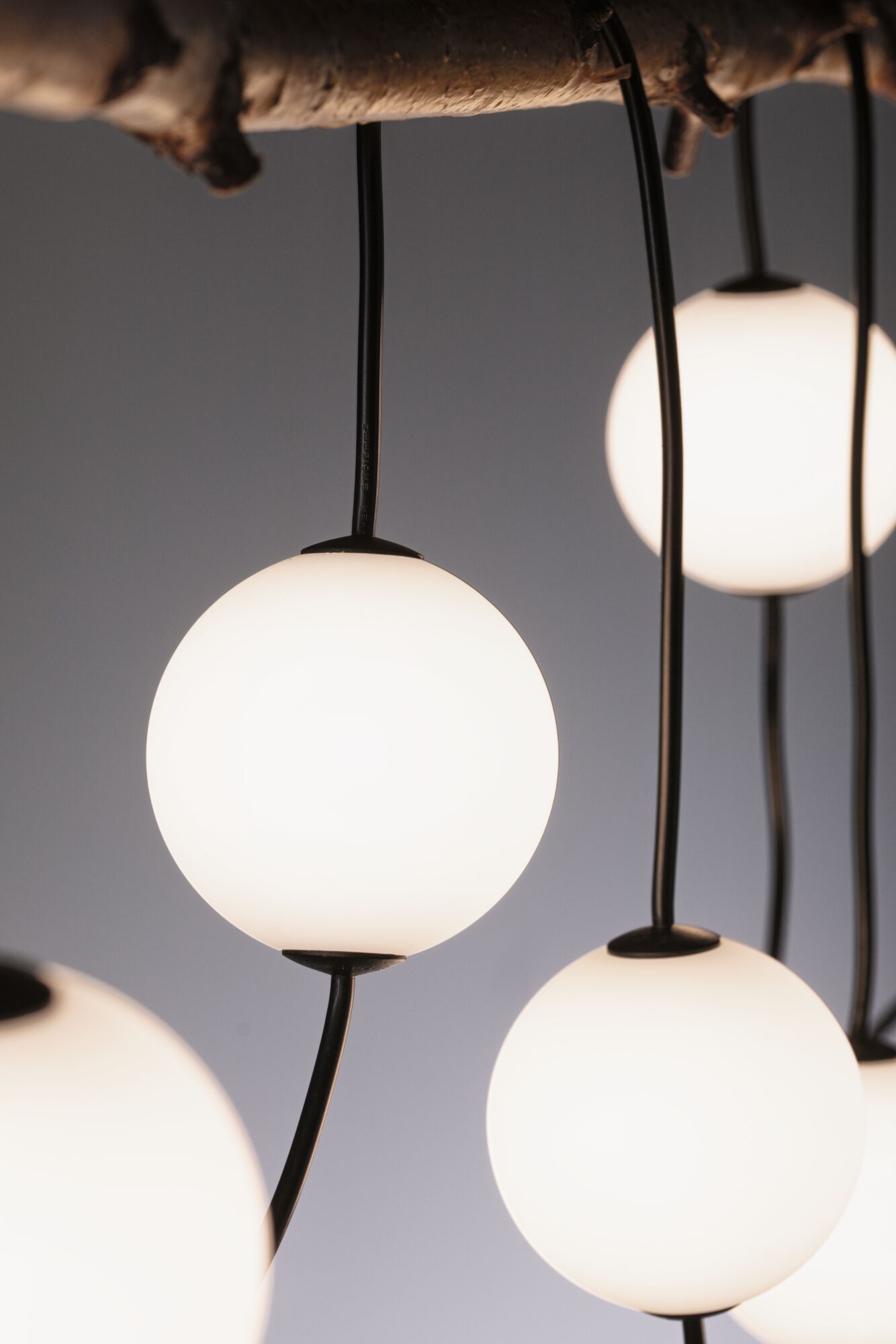 Moderne Pendelleuchte mit weißen Glas-Kugeln und schwarzen Kabeln, stilvolle Raumbeleuchtung