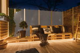 Gezellige buitenlounge met houten palletbank en warm wit LED-licht voor terras en tuin sfeer.