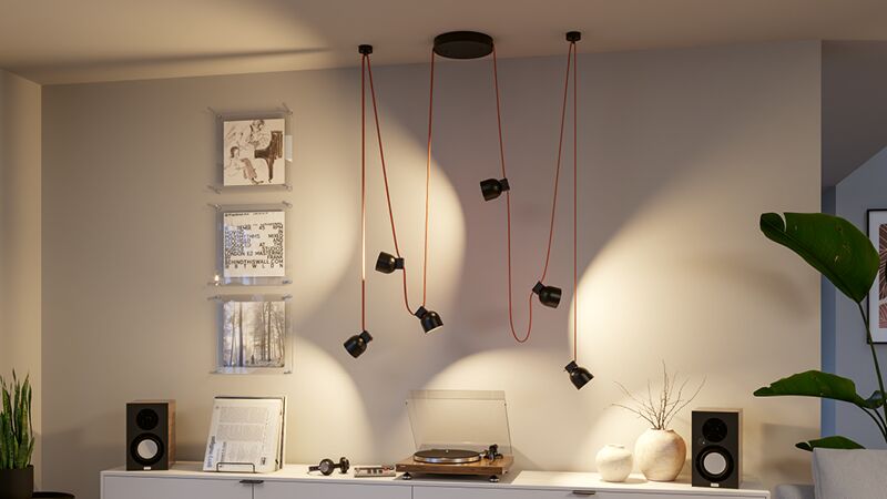 Moderne schwarze LED-Pendelleuchte mit orangem Gurt über Sideboard mit Plattenspieler und Lautsprechern