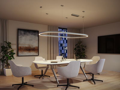 Modern round white LED pendant light with warm white glow above office conference table.