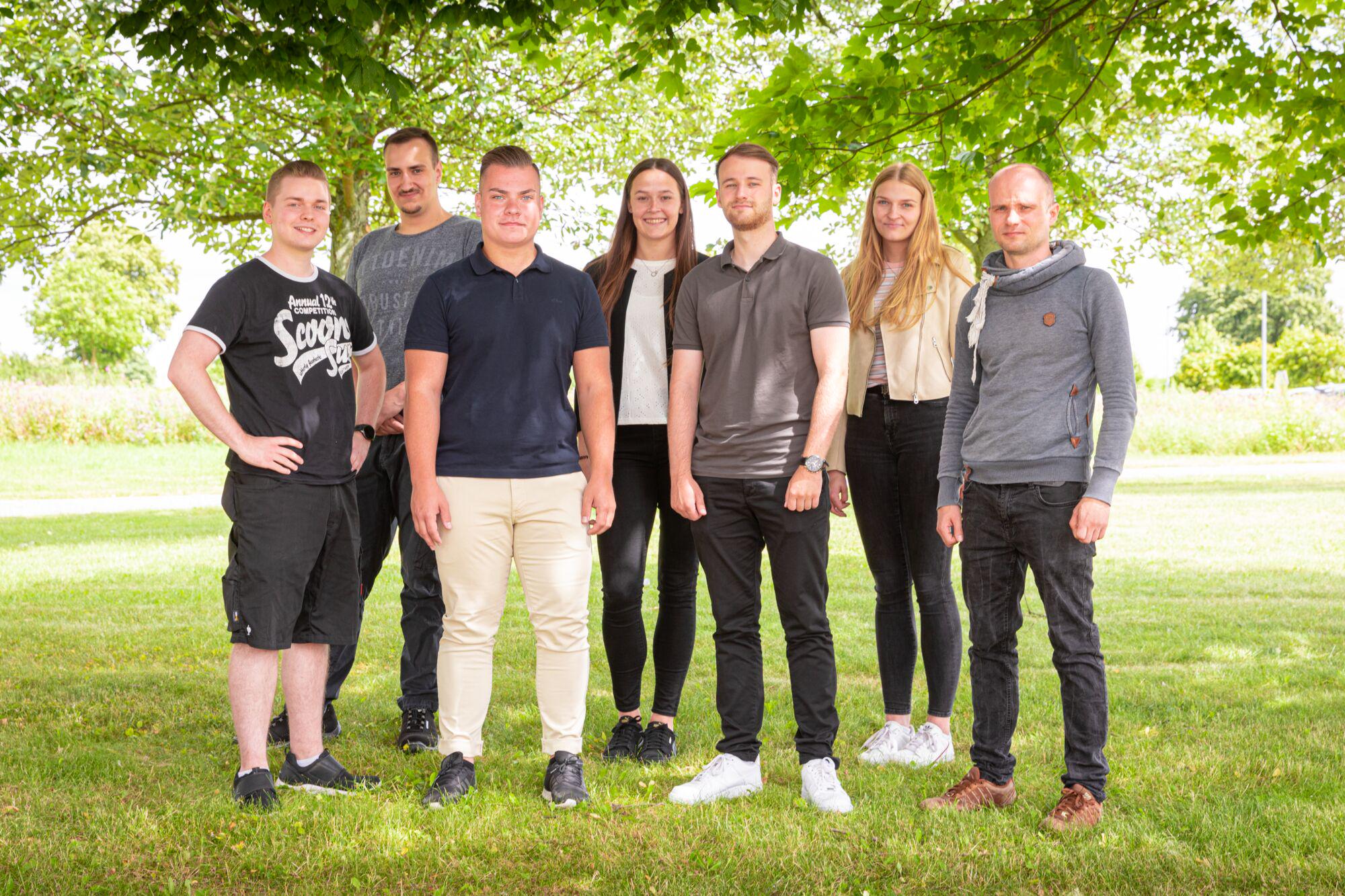 Group of young people standing outdoors under tree – team photo for career and training.