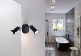 Black LED wall light with two adjustable spots in modern bathroom featuring bathtub and wood floor.