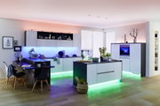 Modern white kitchen island and cabinets with colorful LED underlighting in blue, green, and red.
