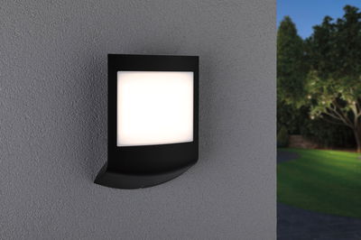 Modern black outdoor wall light with white diffuser on grey wall for garden lighting