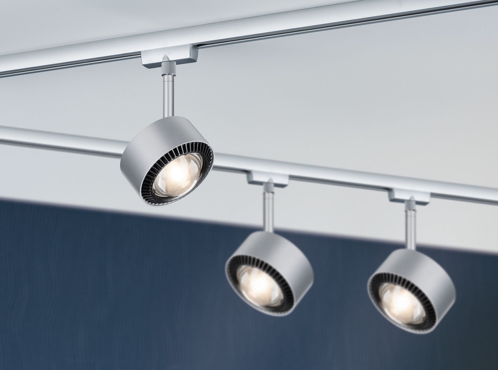 Drei silberne LED-Strahler aus Metall an Schienensystem für flexible Raumbeleuchtung.