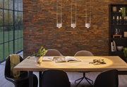 Three white metal LED pendant lights above light wooden table with plants and books in dining room