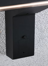 Schwarzes Metallgehäuse an weißer Wand mit kleiner Klappe, modernes Outdoor-Gehäuse