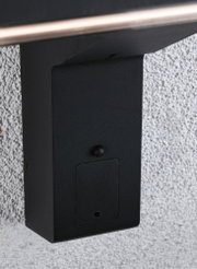 Boîtier métallique noir avec petite trappe fixé sur mur blanc texturé pour éclairage extérieur
