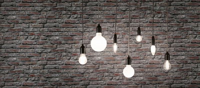 Forskellige filament LED-pærer med varmt hvidt lys foran grå murstensvæg til boligbelysning