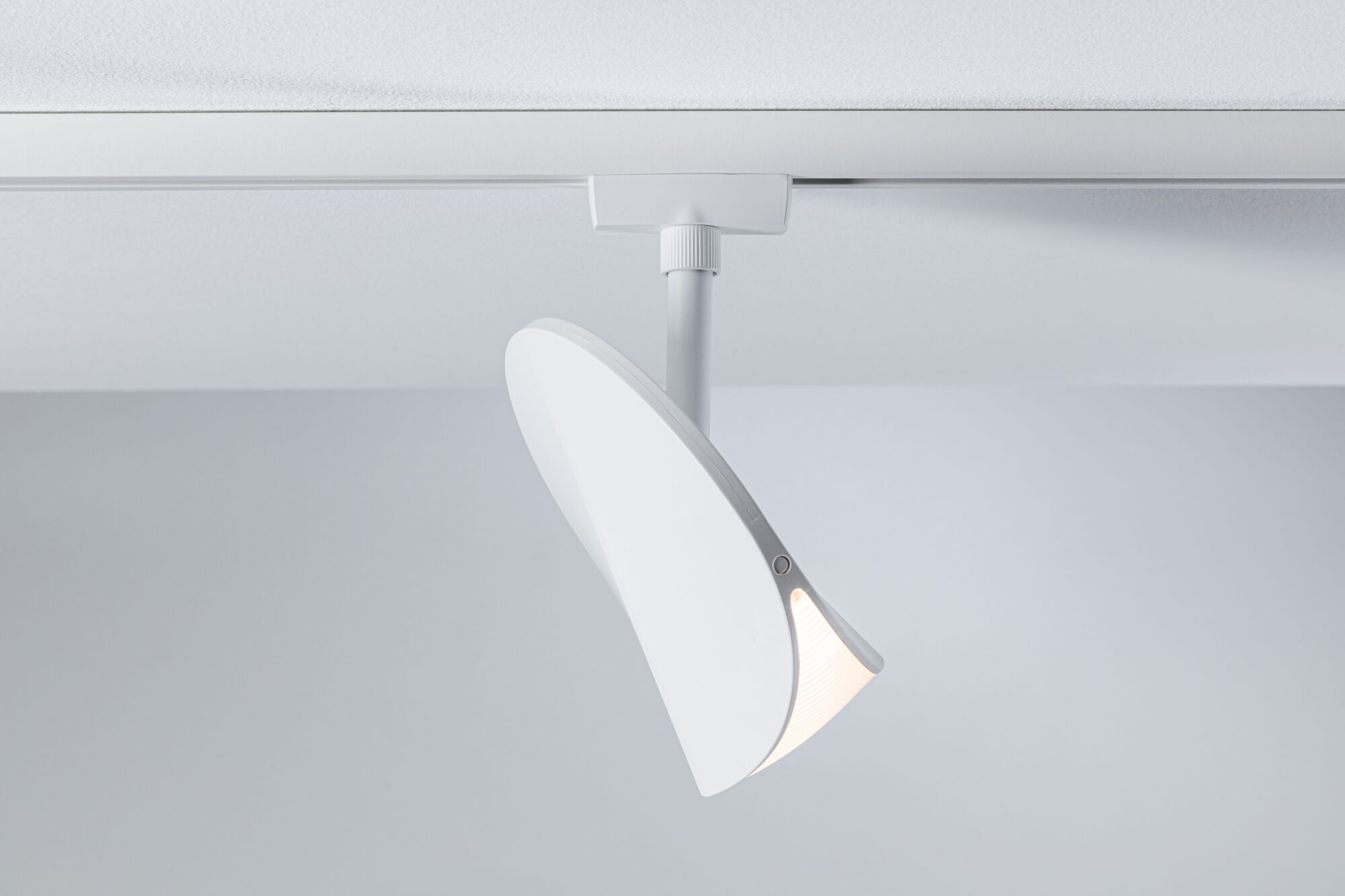 Moderner weißer LED-Strahler aus Kunststoff an Schienensystem für flexible Raumbeleuchtung
