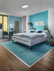 Chambre moderne avec lit blanc, tapis bleu et plafonnier carré pour éclairage ambiant