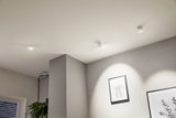 Weiße LED-Deckenstrahler aus Metall beleuchten moderne Wandbilder in minimalistischem Raum.