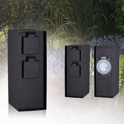 Black outdoor sockets with protective covers and mechanical timer for garden lighting control.
