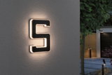 Leuchtende Hausnummer 5 aus schwarzem Material mit warmweißem LED-Licht an grauer Wand im Außenbereich