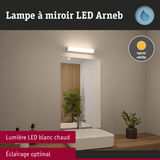 Lampe à miroir LED Arneb avec lumière blanc chaud au-dessus d'un lavabo blanc et plan de travail en bois