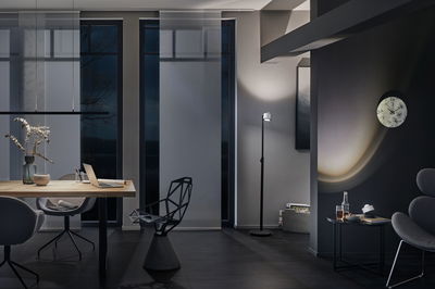 Salon moderne avec chaise design noire, lampe sur pied et horloge murale en marbre dans un intérieur sombre