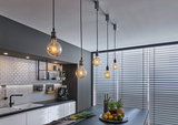 Modern kitchen with black countertops, white tiles, and five hanging light bulbs for ambient lighting