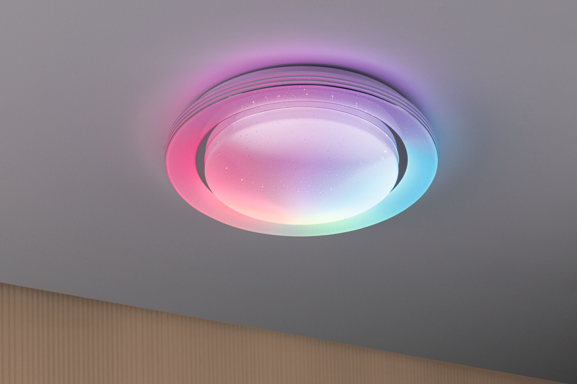 Plafonnier rond en plastique blanc avec éclairage LED multicolore pour pièces à vivre.